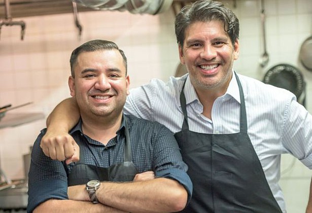 Deux cuisiniers regardent le photographe, les deux hommes sourient.